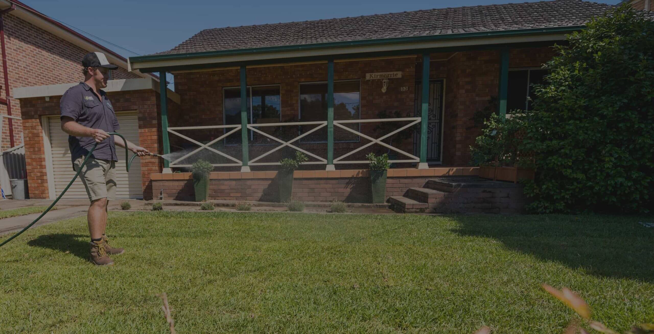 One of Musturf Staff Spraying Water To The Lawn