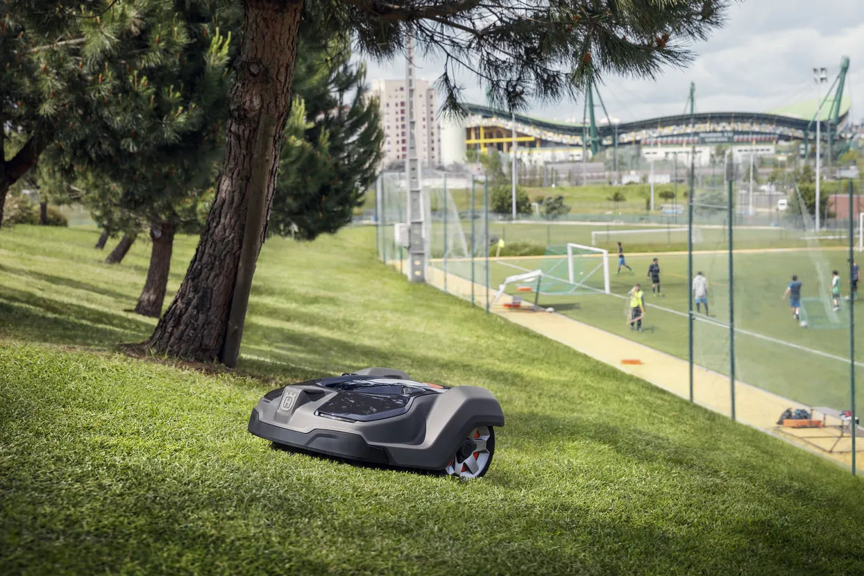 Husqvarna 450X Automower® working on a turf grass beside a football field